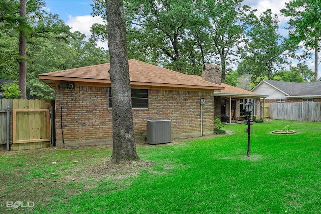 rear view of house with a lawn and central AC