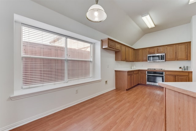 kitchen featuring lofted ceiling, light wood-type flooring, stainless steel appliances, and decorative light fixtures