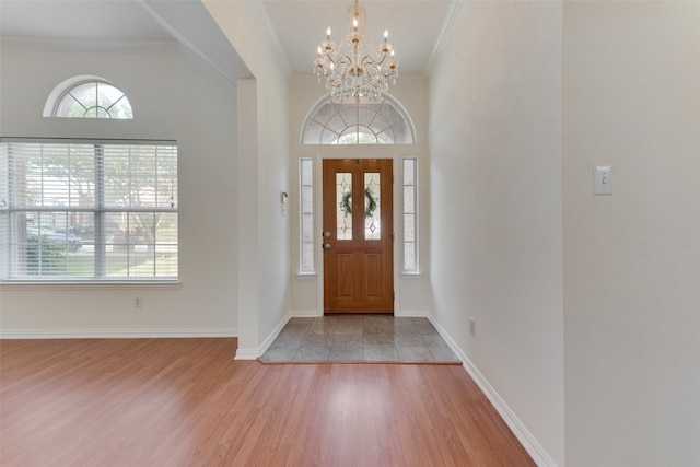 entrance foyer with light hardwood / wood-style floors, a notable chandelier, and crown molding