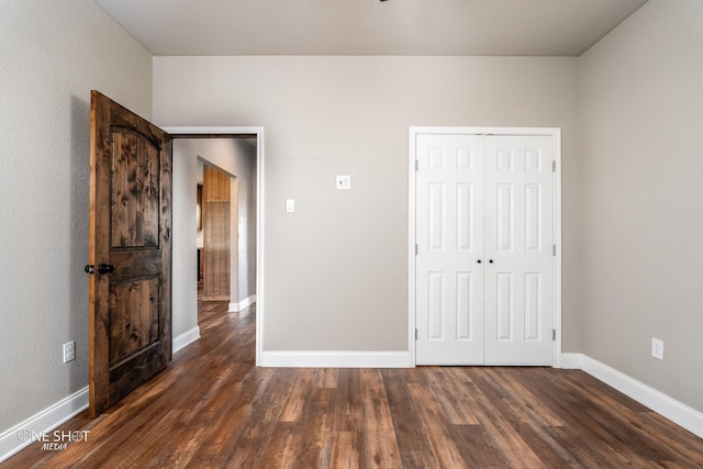 unfurnished bedroom with a closet and dark wood-type flooring