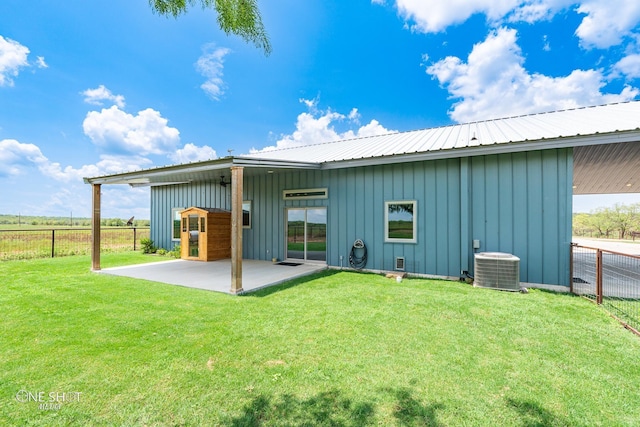 rear view of property with cooling unit, a yard, and a patio