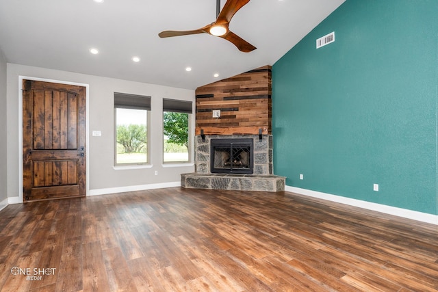 unfurnished living room featuring hardwood / wood-style floors, ceiling fan, a stone fireplace, and vaulted ceiling