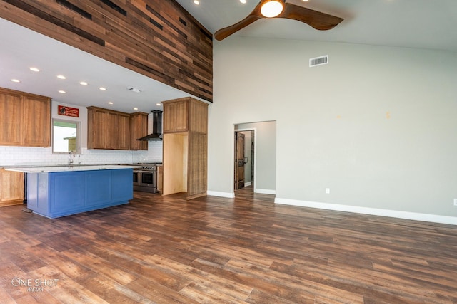 kitchen featuring double oven range, high vaulted ceiling, wall chimney exhaust hood, tasteful backsplash, and a kitchen island