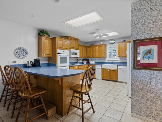 kitchen with kitchen peninsula, a breakfast bar, white appliances, and light tile patterned floors