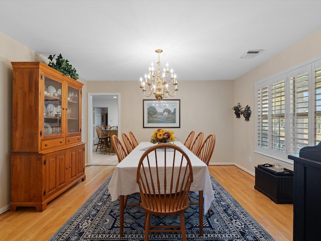 dining area featuring light hardwood / wood-style flooring and a notable chandelier