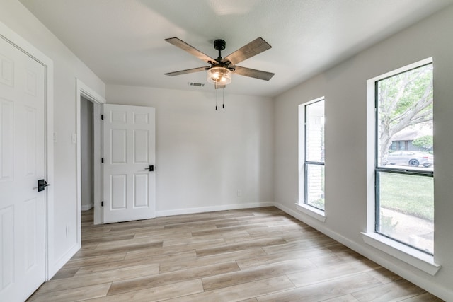 empty room with ceiling fan and light hardwood / wood-style floors