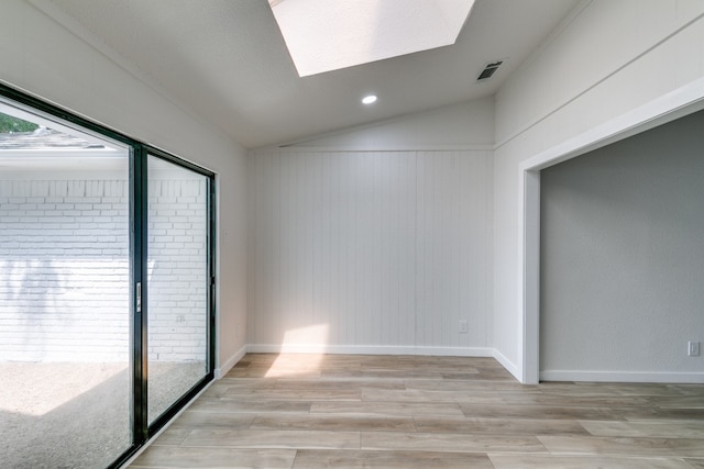 empty room featuring wood-type flooring and vaulted ceiling with skylight