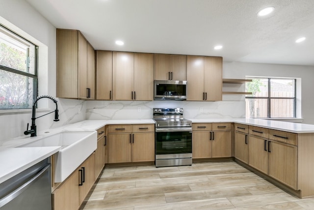 kitchen with appliances with stainless steel finishes, light wood-type flooring, tasteful backsplash, and sink