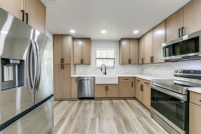 kitchen featuring light hardwood / wood-style flooring, light brown cabinets, appliances with stainless steel finishes, decorative backsplash, and sink