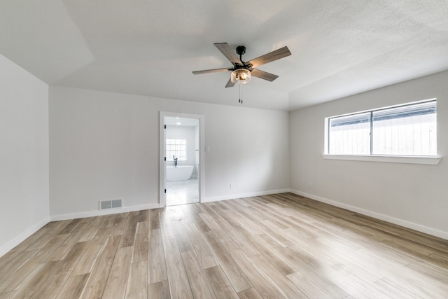 spare room featuring light hardwood / wood-style flooring, a textured ceiling, ceiling fan, and a wealth of natural light