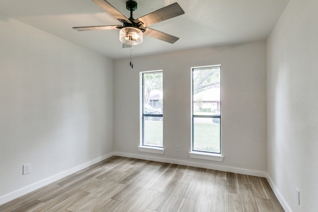 empty room featuring a healthy amount of sunlight, light wood-type flooring, and ceiling fan