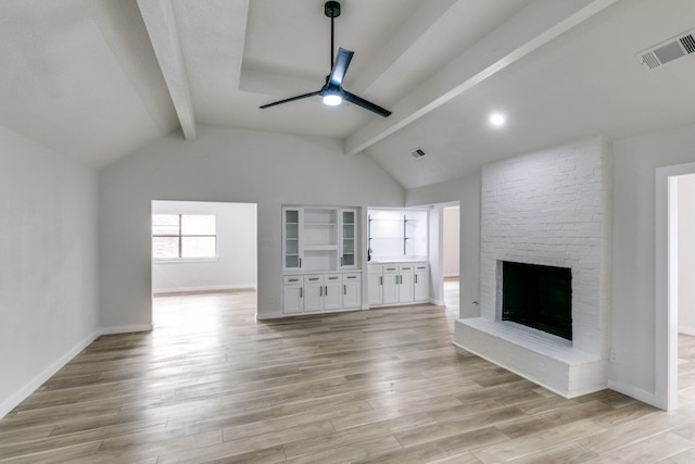 unfurnished living room with vaulted ceiling with beams, a fireplace, light hardwood / wood-style floors, brick wall, and ceiling fan