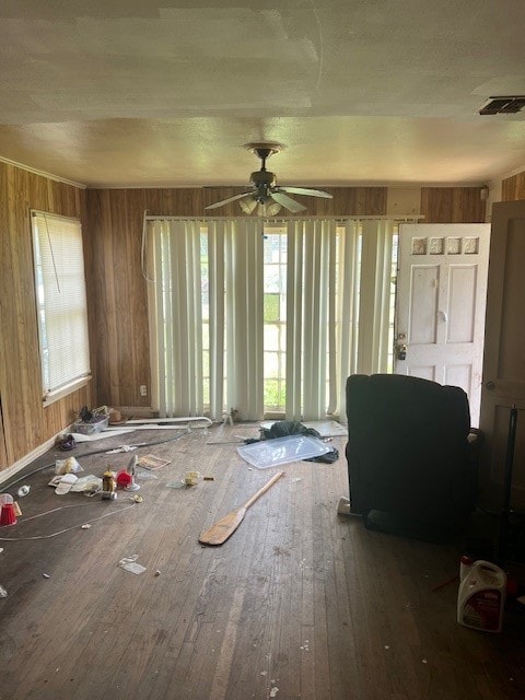 misc room featuring wood walls, ceiling fan, and wood-type flooring