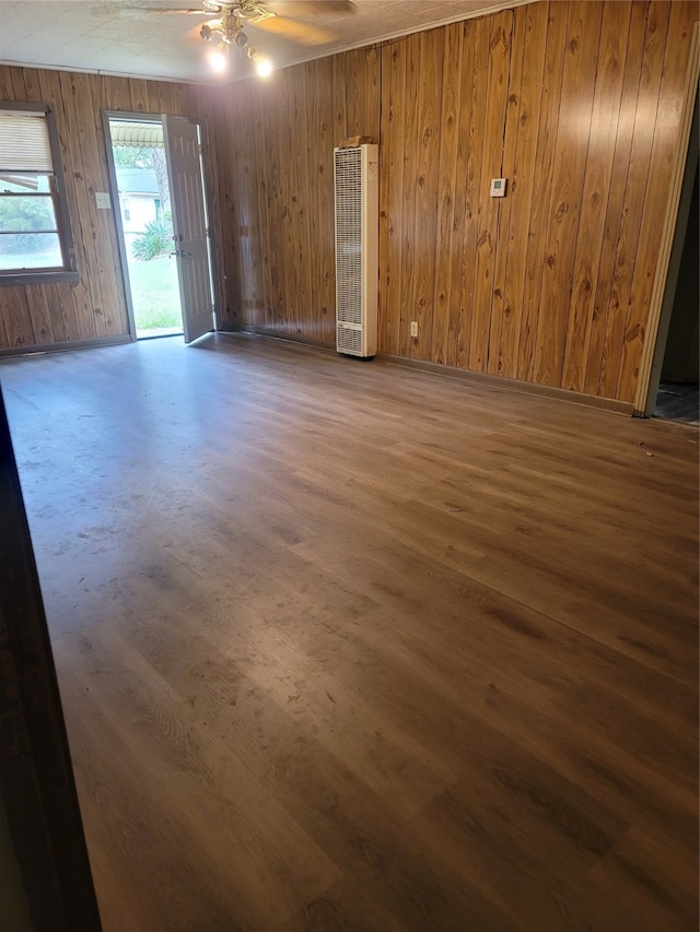 empty room with ceiling fan, wood-type flooring, and wood walls