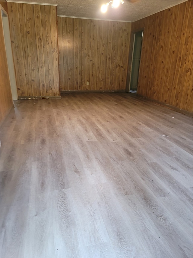 empty room with wood walls and light hardwood / wood-style flooring