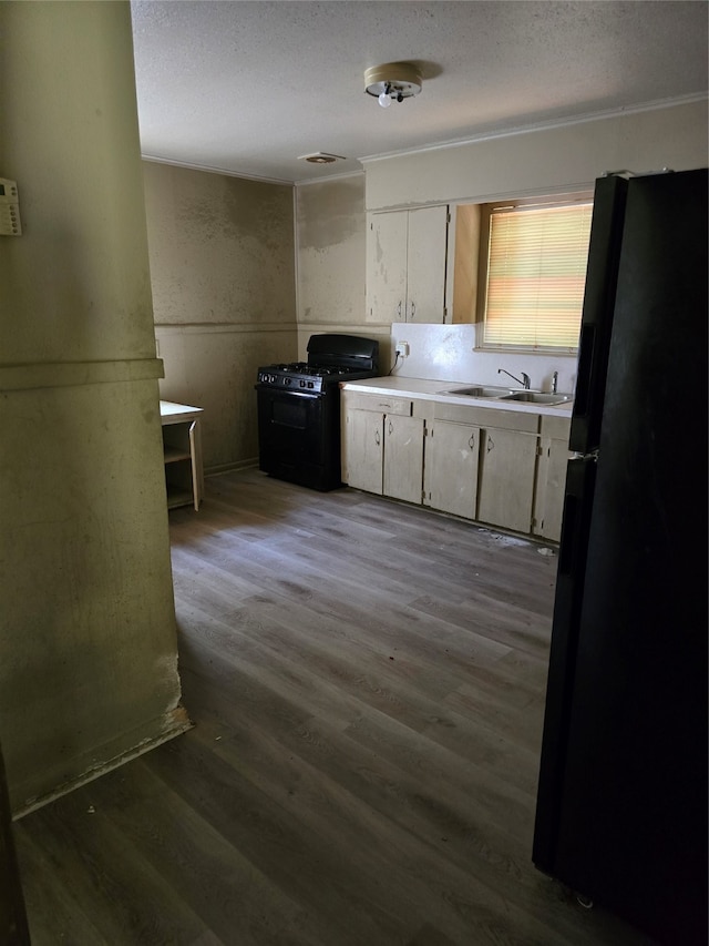 kitchen with white cabinets, sink, wood-type flooring, and black appliances