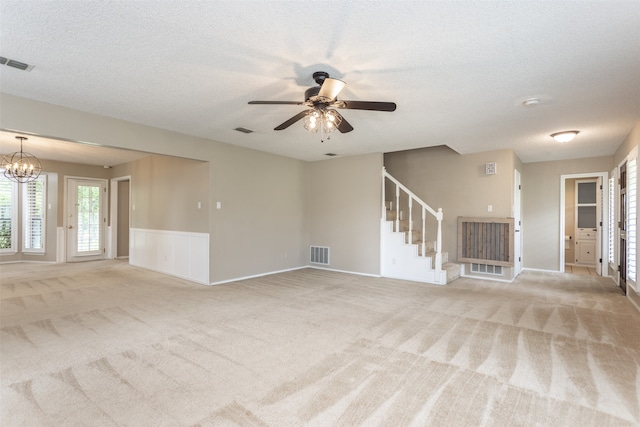 unfurnished living room featuring ceiling fan with notable chandelier, light colored carpet, and a textured ceiling