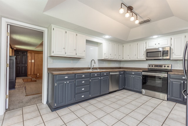 kitchen featuring gray cabinets, stainless steel appliances, light carpet, a raised ceiling, and sink