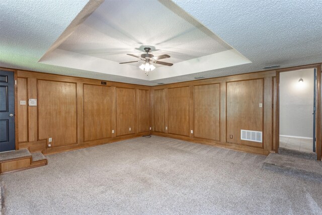 basement featuring a textured ceiling, ceiling fan, and light carpet