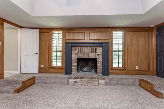 unfurnished living room featuring a textured ceiling, a brick fireplace, and light colored carpet