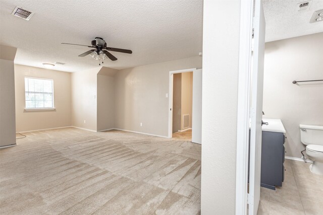 interior space with light carpet, ceiling fan, and a textured ceiling