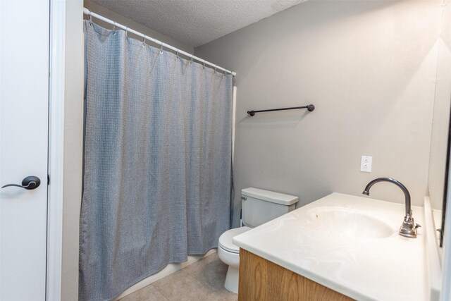 bathroom with tile patterned floors, toilet, vanity, and a textured ceiling