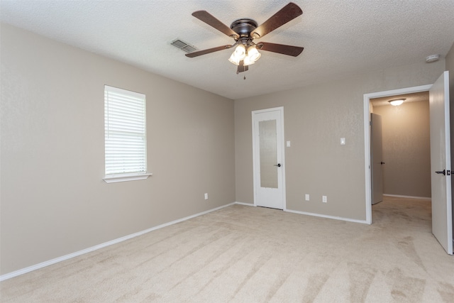 unfurnished bedroom featuring a textured ceiling, light colored carpet, and ceiling fan