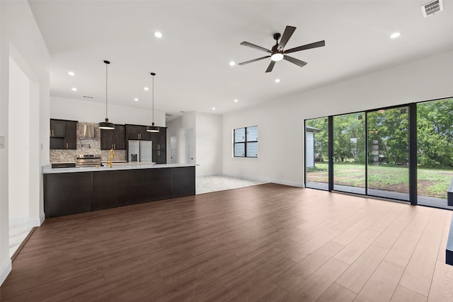 kitchen featuring ceiling fan, tasteful backsplash, wall chimney exhaust hood, dark brown cabinetry, and appliances with stainless steel finishes