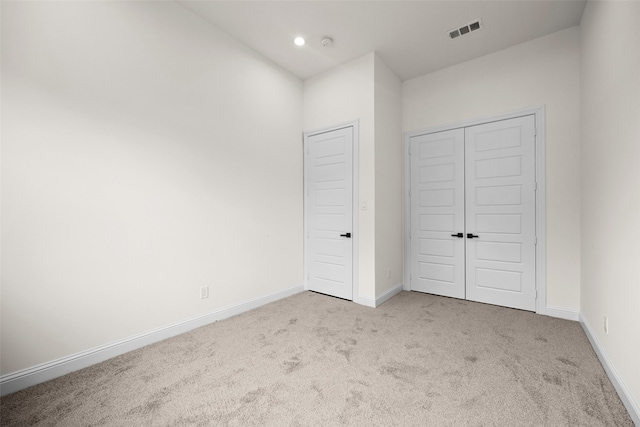 unfurnished bedroom featuring a closet and light colored carpet