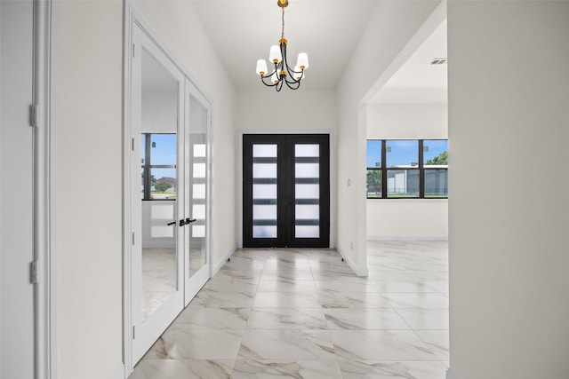 foyer with french doors, light tile patterned floors, and an inviting chandelier