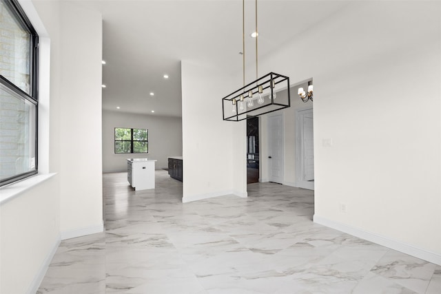 1057 Meadow Hill Dr, Lavon, TX 75166 - unfurnished dining area with baseboards, light marble finish flooring, recessed lighting, a chandelier, and a towering ceiling