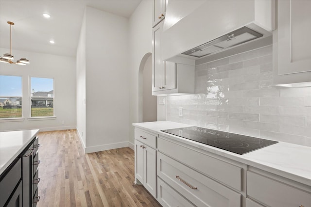 kitchen with white cabinetry, light wood-type flooring, black electric stovetop, decorative backsplash, and wall chimney range hood