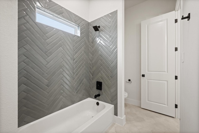 bathroom featuring tile patterned flooring, tiled shower / bath, and toilet