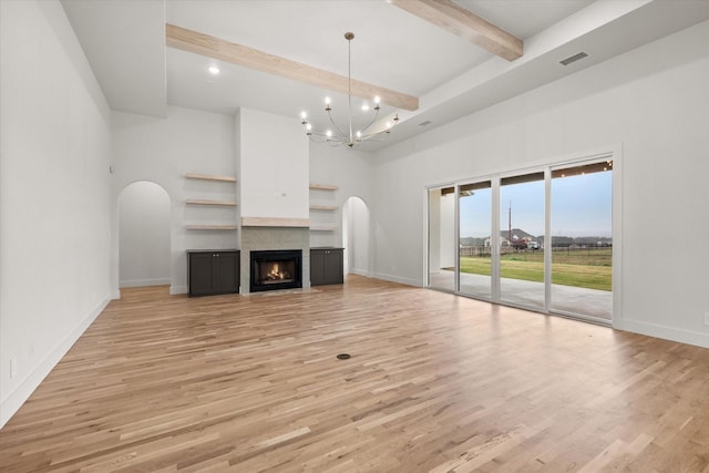 unfurnished living room featuring an inviting chandelier, a high ceiling, beamed ceiling, and light wood-type flooring