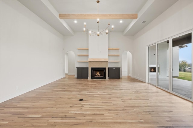 unfurnished living room with an inviting chandelier, beam ceiling, and light hardwood / wood-style floors