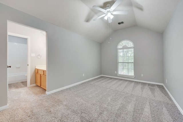 unfurnished bedroom featuring ceiling fan, lofted ceiling, light colored carpet, and ensuite bath