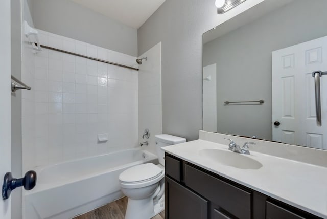 full bathroom with hardwood / wood-style flooring, tiled shower / bath combo, vanity, and toilet