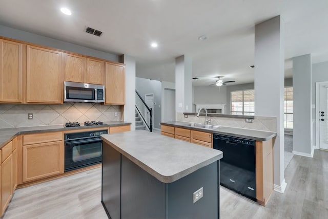 kitchen featuring a kitchen island, black appliances, decorative backsplash, sink, and light hardwood / wood-style flooring