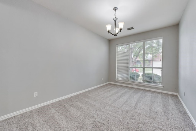 spare room with carpet flooring and a notable chandelier