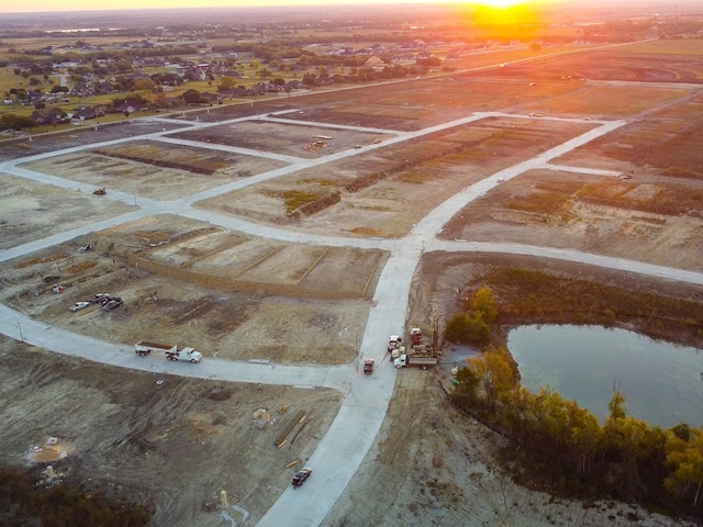 aerial view at dusk featuring a water view