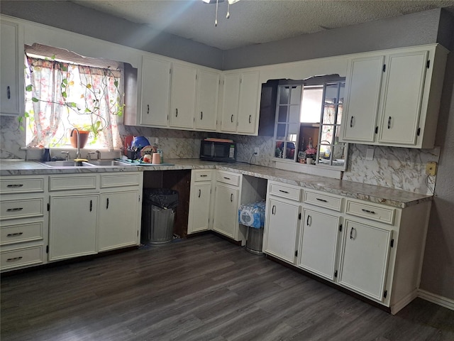 kitchen featuring sink, dark hardwood / wood-style floors, decorative backsplash, a textured ceiling, and white cabinetry