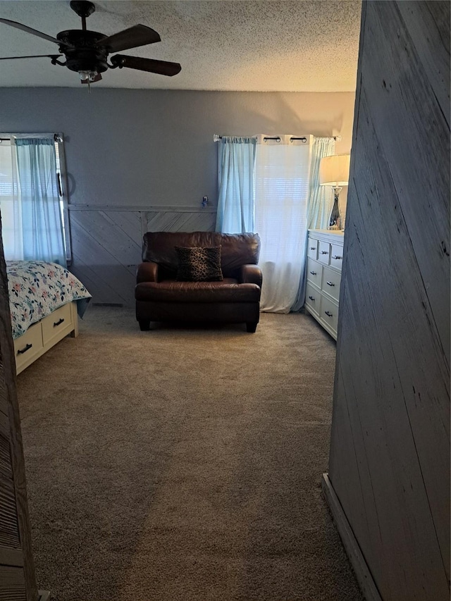 carpeted bedroom with a textured ceiling, ceiling fan, and wooden walls