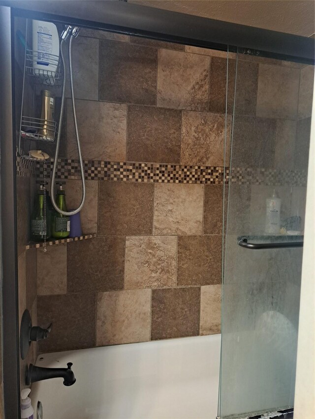 bathroom with bath / shower combo with glass door