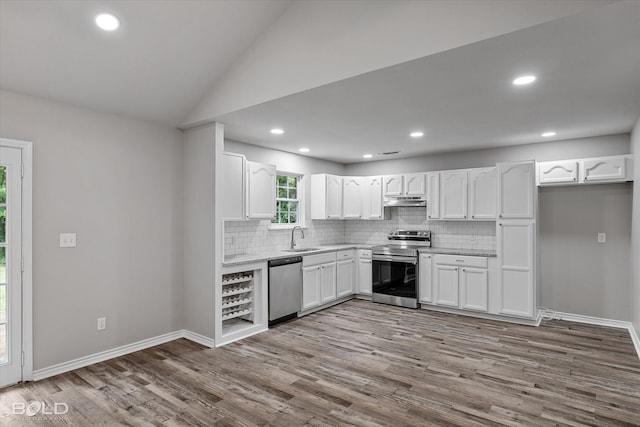 kitchen with light hardwood / wood-style flooring, backsplash, appliances with stainless steel finishes, white cabinetry, and lofted ceiling