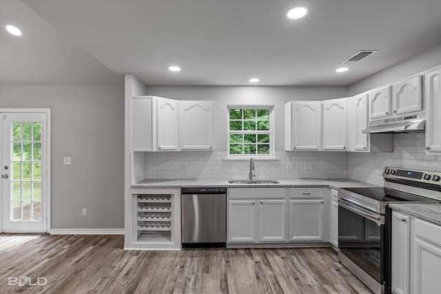 kitchen with stainless steel appliances, decorative backsplash, white cabinetry, and light hardwood / wood-style flooring