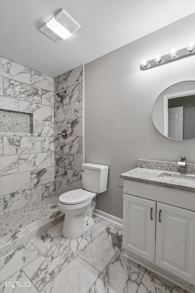 bathroom featuring tiled shower, toilet, and vanity