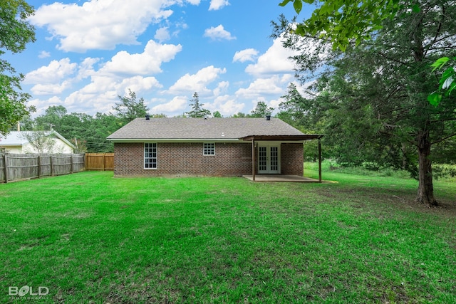 back of property with french doors, a patio area, and a yard