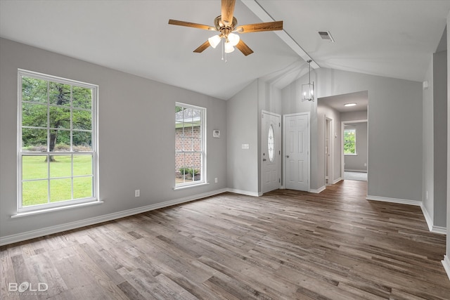 unfurnished living room featuring a wealth of natural light, wood-type flooring, and lofted ceiling with beams