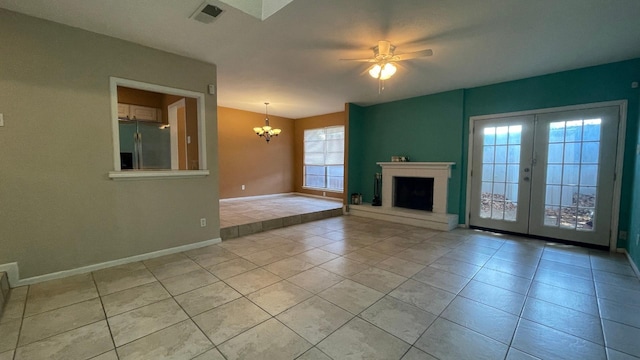 unfurnished living room featuring french doors, light tile patterned floors, and ceiling fan with notable chandelier