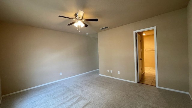 unfurnished bedroom featuring ceiling fan, light carpet, and a spacious closet